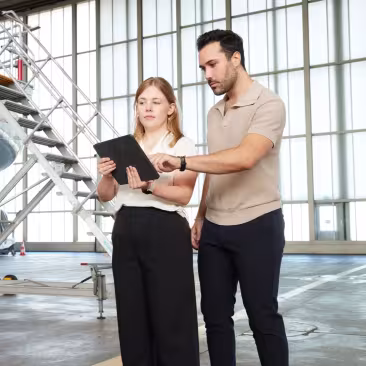 two people in a hangar with a tablet